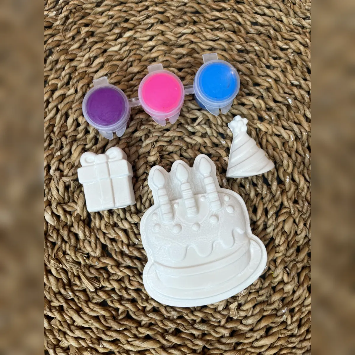 White plaster birthday cake, gift, and party hat with purple, pink, and blue paint